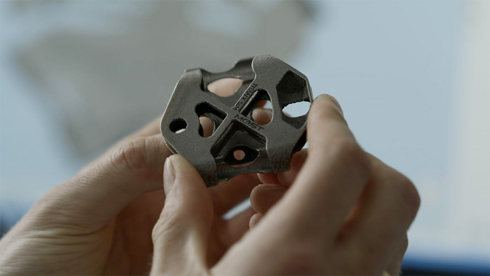 Person, die ein 3D-gedrucktes Metallteil für das Pinarello-Rennrad hält 