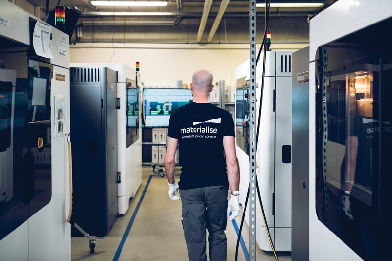 Man walking in between rows of 3D printers 