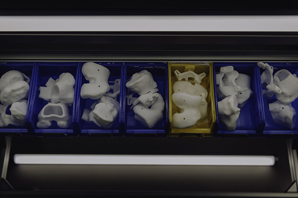 An image of 3D-printed anatomical models, knee surgical guides, and metal CMF guides and implants.