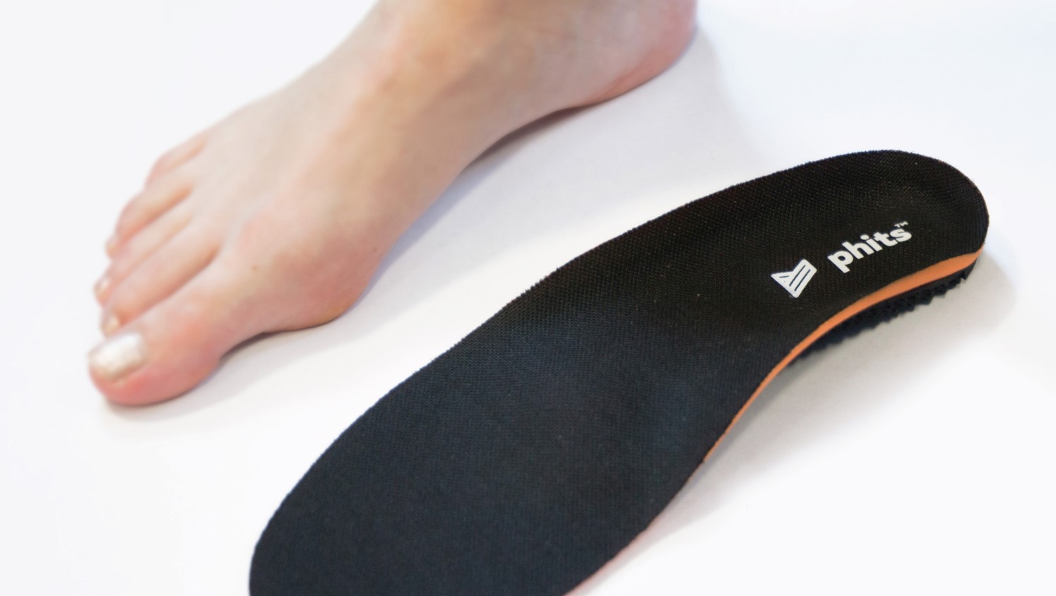 Close up of a bare foot side by side with a 3D-printed phits orthotic insole 