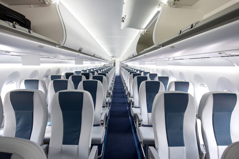 Commercial aircraft cabin with rows of seats down the aisle