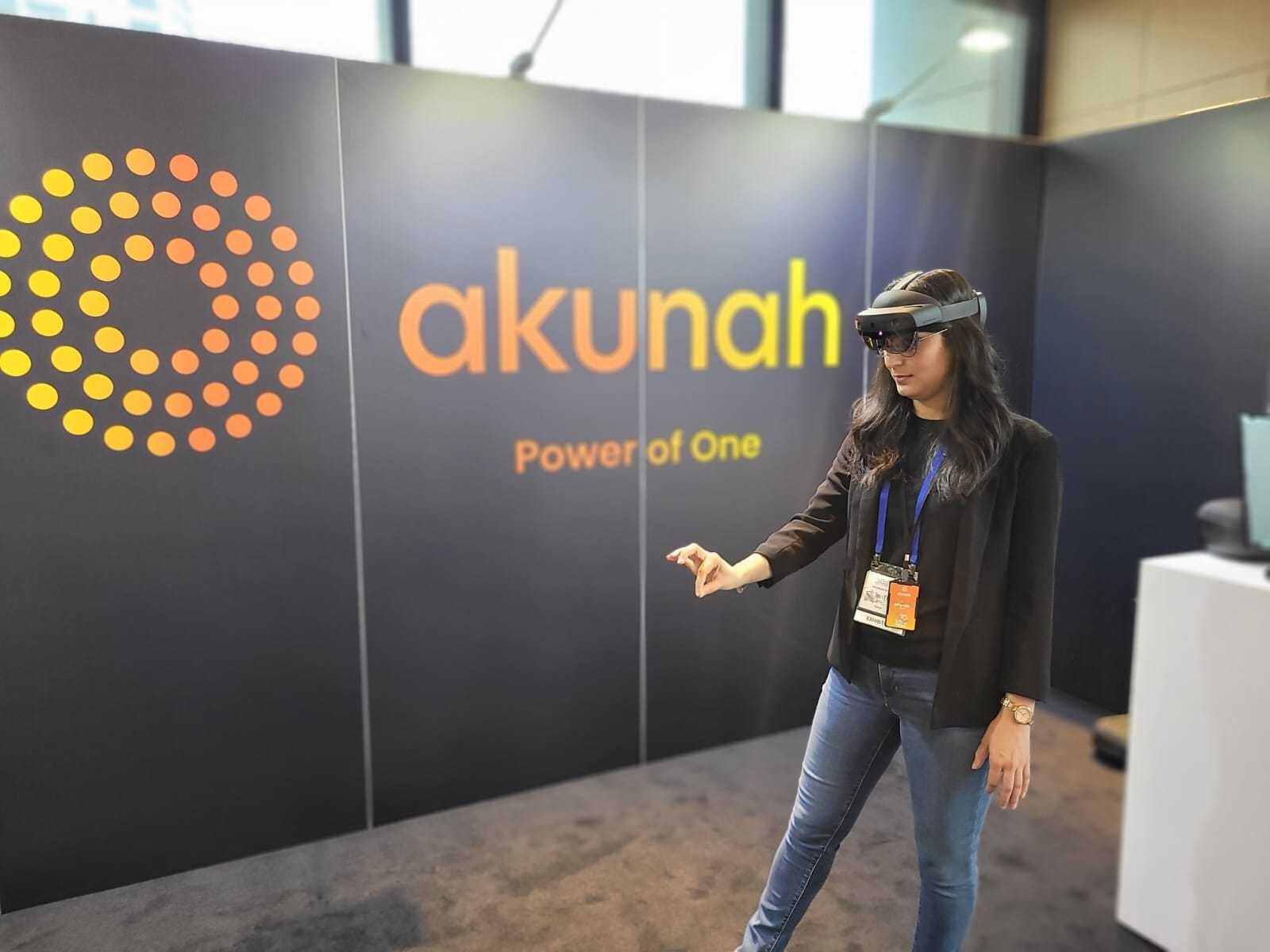 Woman with Hololens on in front of a wall with the Akunah logo
