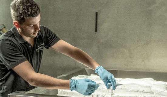 A Materialise employee removes a 3D-printed phits orthotic from its powder bed