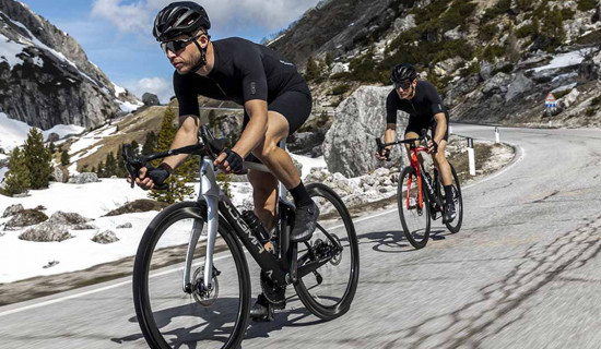 Two cyclists riding Pinarello’s new racing bike on a mountain road 